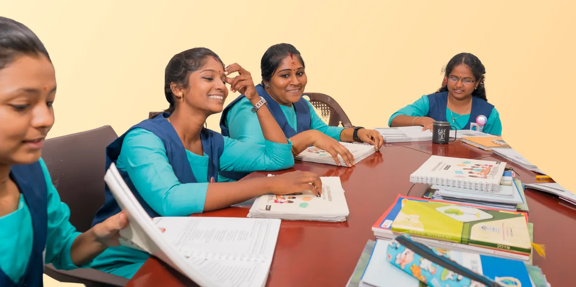 Smiling teachers planning lessons together with Chrysalis books and materials